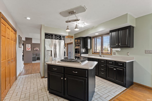 kitchen featuring a sink, appliances with stainless steel finishes, dark cabinetry, and light countertops