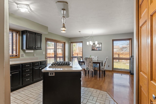 kitchen with stainless steel gas stovetop, dark cabinets, a center island, and light countertops