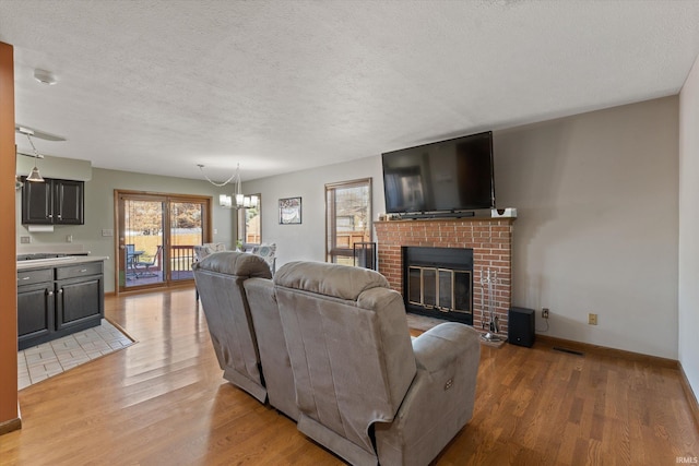 living room with a fireplace, a notable chandelier, light wood-style floors, and visible vents