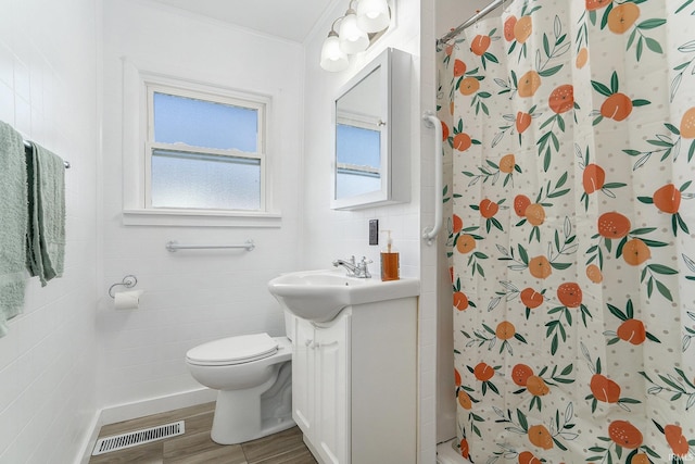 bathroom with visible vents, a shower with curtain, toilet, wood finished floors, and vanity