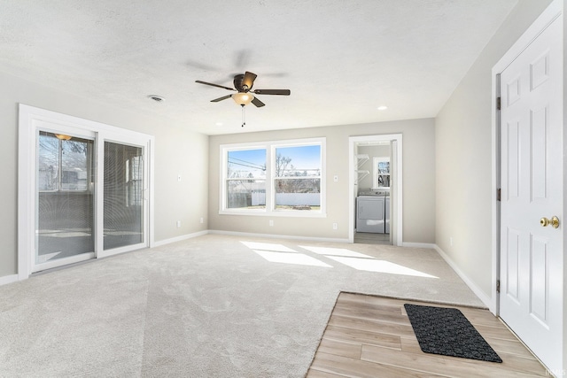 interior space featuring light carpet, a textured ceiling, baseboards, washer / dryer, and ceiling fan