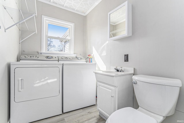 half bath featuring vanity, wood finished floors, an ornate ceiling, washer and dryer, and toilet