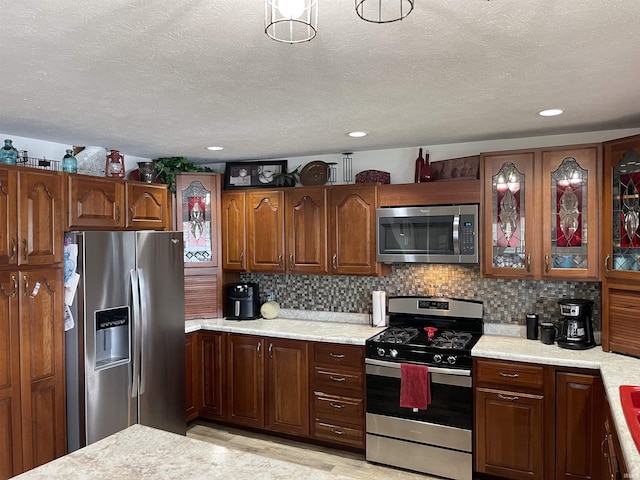 kitchen with recessed lighting, decorative backsplash, glass insert cabinets, appliances with stainless steel finishes, and a textured ceiling