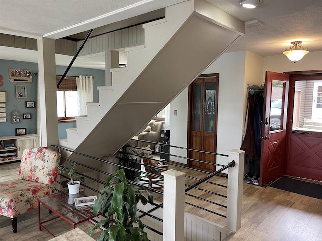 foyer entrance featuring a textured ceiling, wood finished floors, and stairs