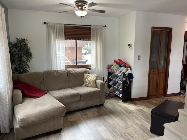 living room featuring a ceiling fan, light wood-style floors, and baseboards