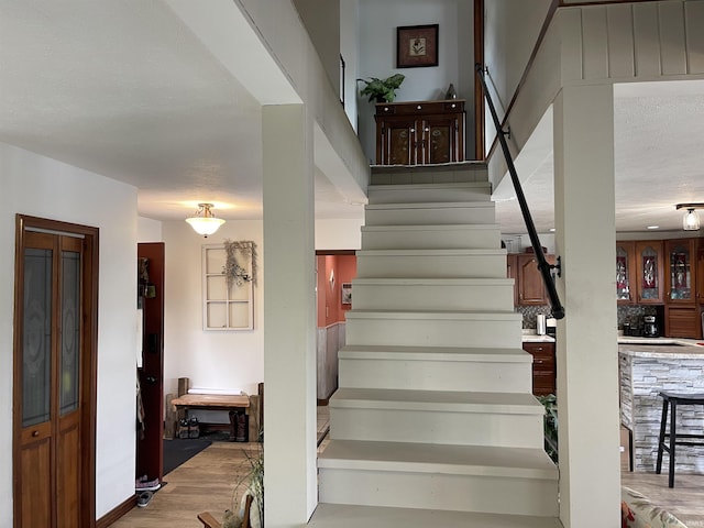 stairs with a textured ceiling and wood finished floors