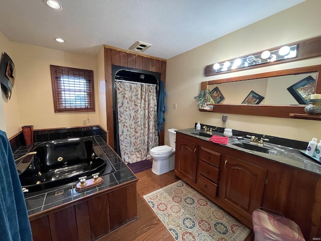 full bathroom with visible vents, toilet, a whirlpool tub, a textured ceiling, and vanity