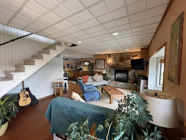 living room featuring stairs, a stone fireplace, and wood finished floors