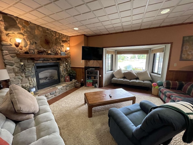 living area featuring a fireplace, wood walls, and wainscoting