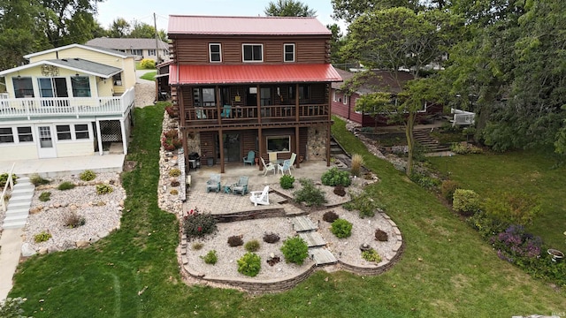 rear view of property featuring stairway, a wooden deck, a patio area, a lawn, and metal roof