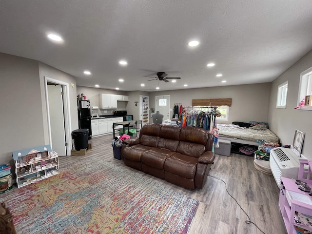 living room featuring recessed lighting, light wood-style flooring, a textured ceiling, and ceiling fan