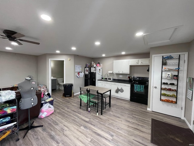 interior space with dark countertops, light wood-type flooring, white cabinets, black appliances, and a ceiling fan