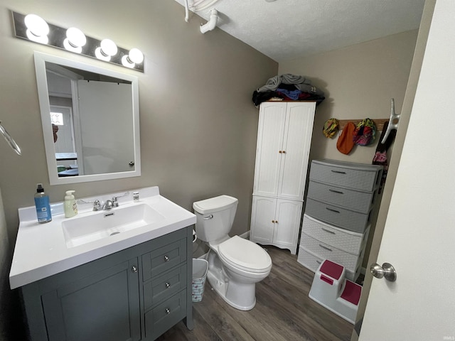 bathroom featuring toilet, wood finished floors, vanity, and a textured ceiling