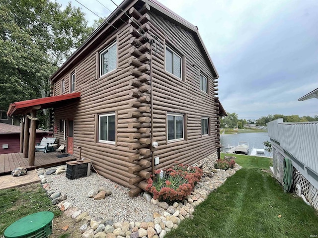 view of property exterior with log siding, a lawn, and a deck with water view