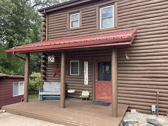 view of exterior entry featuring log siding and metal roof