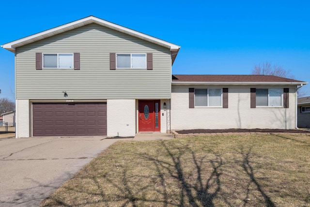 split level home featuring a front yard, brick siding, concrete driveway, and an attached garage