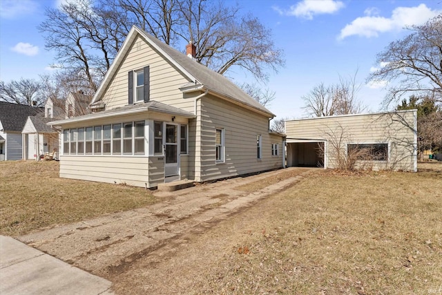 view of front of property with an outdoor structure, a sunroom, and a chimney