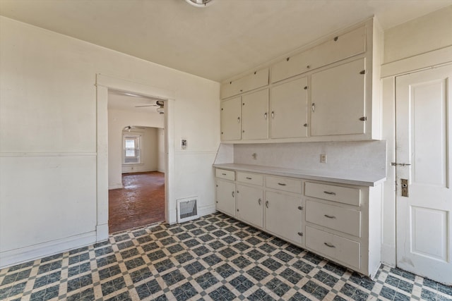 kitchen with visible vents, light countertops, a ceiling fan, and dark floors