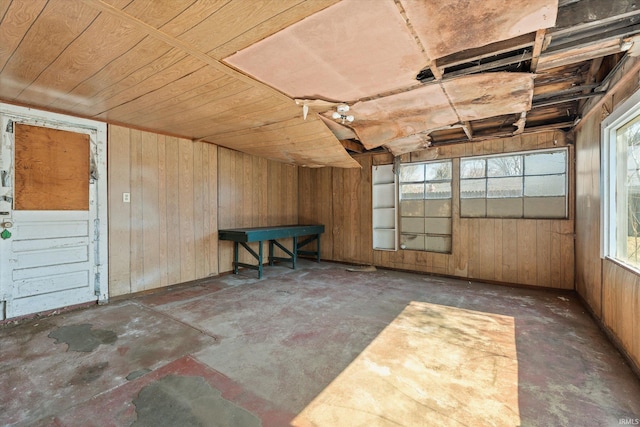 misc room with wooden ceiling, a garage, concrete floors, and wood walls