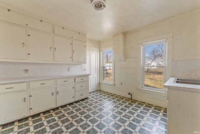 kitchen featuring light countertops, a healthy amount of sunlight, light floors, and a sink