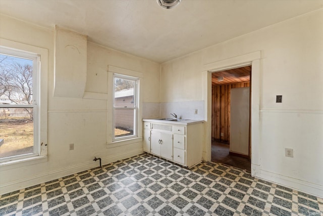 kitchen with baseboards, a sink, light countertops, white cabinets, and tile patterned floors