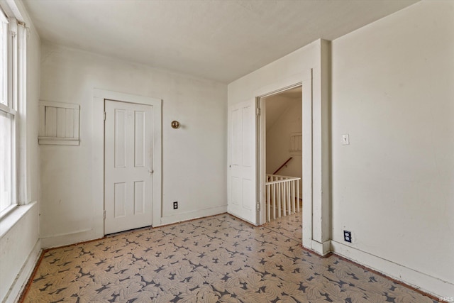 spare room featuring light colored carpet and baseboards