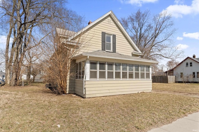 exterior space featuring roof with shingles, fence, a yard, and a sunroom