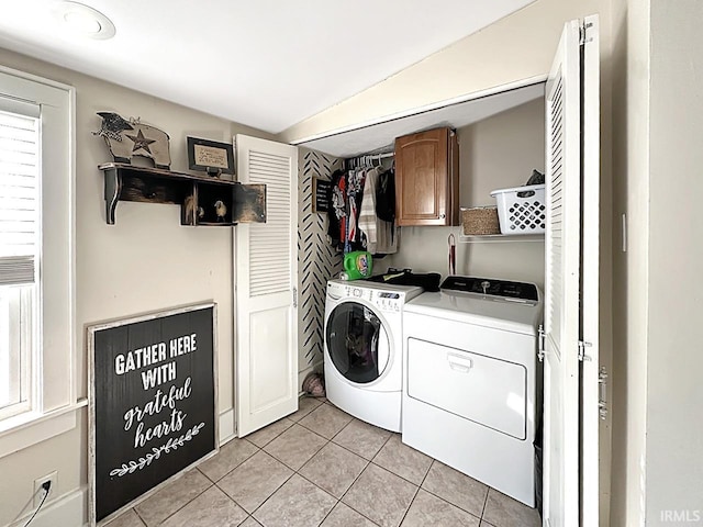 clothes washing area featuring light tile patterned floors, cabinet space, and independent washer and dryer