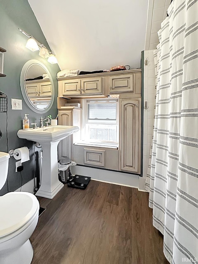 full bathroom with curtained shower, toilet, wood finished floors, and a sink