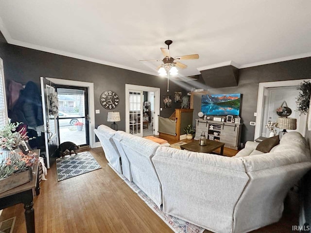 living area with ornamental molding, wood finished floors, and ceiling fan