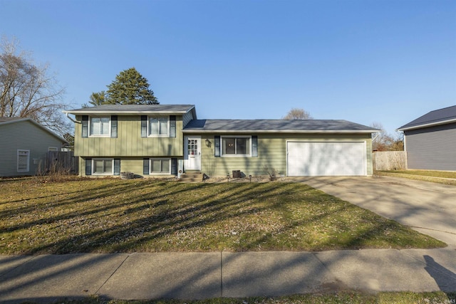 tri-level home featuring a garage, a front lawn, driveway, and fence