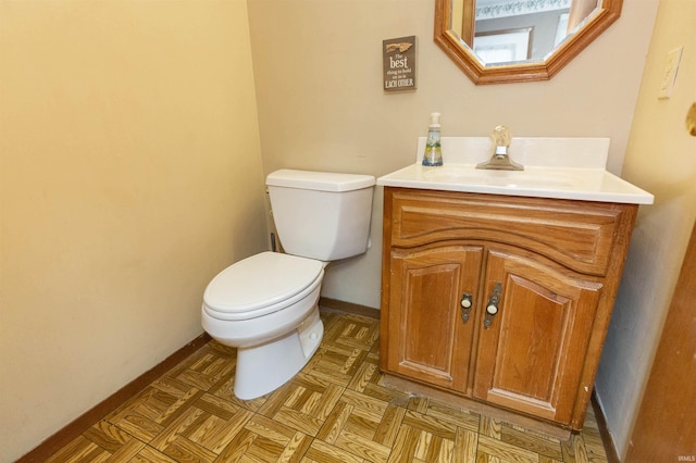 bathroom with baseboards, toilet, and vanity