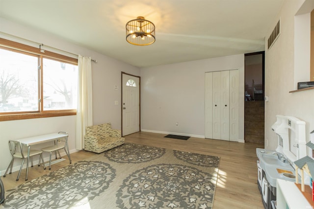 foyer entrance featuring light wood-type flooring, baseboards, a notable chandelier, and visible vents