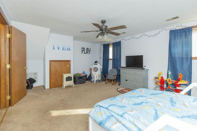 carpeted bedroom featuring visible vents, a textured ceiling, and ceiling fan