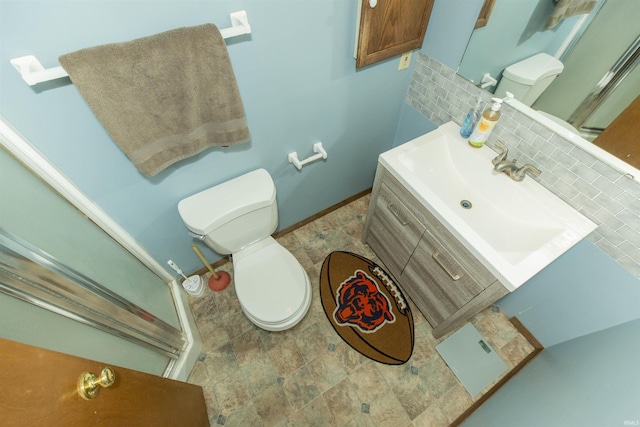 bathroom with vanity, toilet, baseboards, and backsplash