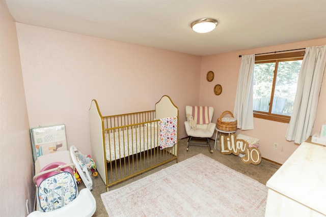 bedroom with a crib, carpet, and baseboards