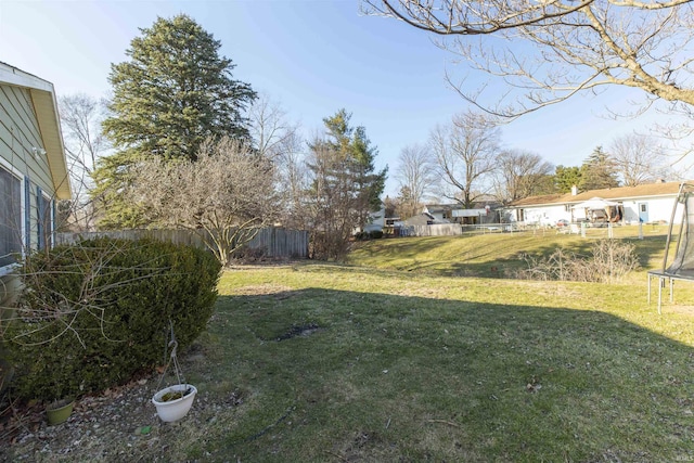 view of yard with a trampoline and fence