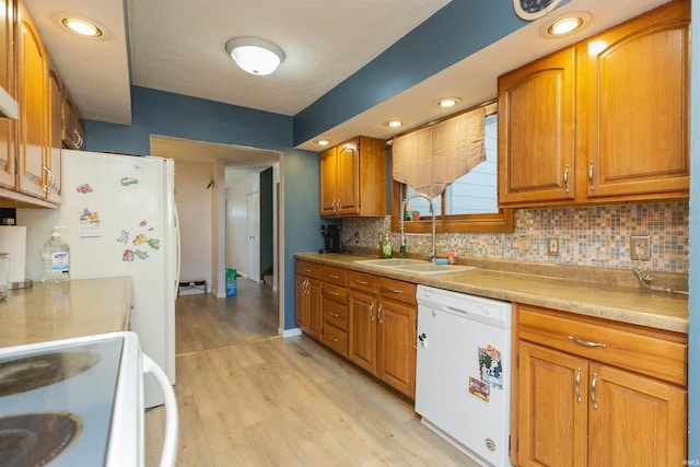 kitchen featuring dishwasher, light wood-style flooring, brown cabinetry, and a sink