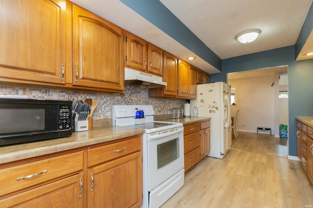 kitchen with under cabinet range hood, white appliances, brown cabinetry, light wood finished floors, and light countertops