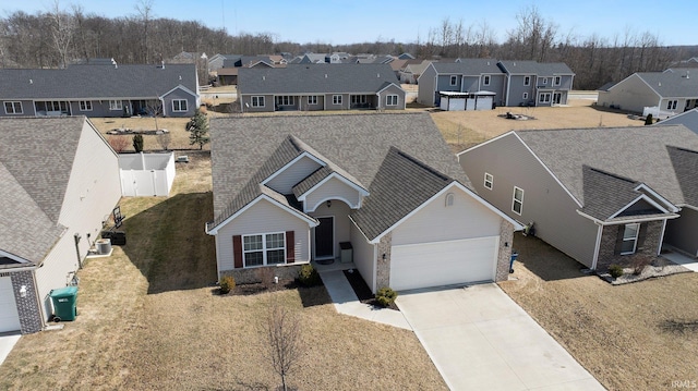 view of front of home featuring fence, driveway, an attached garage, central AC, and a residential view