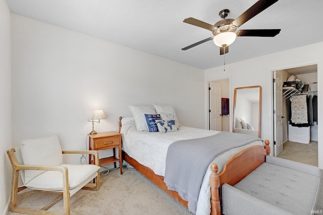 bedroom with a walk in closet, a textured ceiling, a closet, and a ceiling fan