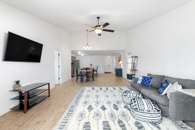 living room featuring a ceiling fan, light wood-style floors, and high vaulted ceiling