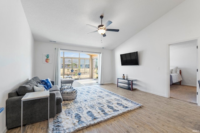 living area featuring a textured ceiling, wood finished floors, a ceiling fan, and vaulted ceiling