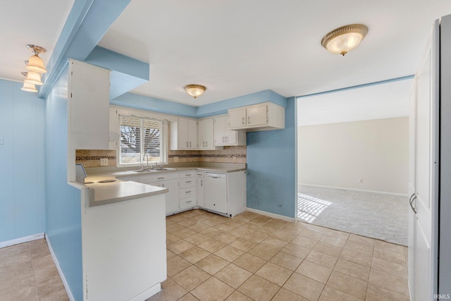 kitchen featuring a sink, tasteful backsplash, a peninsula, and light countertops