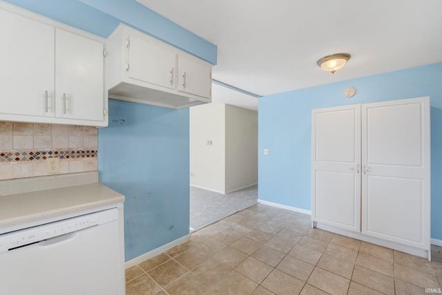 kitchen featuring tasteful backsplash, baseboards, light countertops, white dishwasher, and white cabinetry