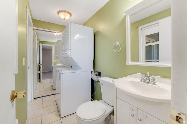 half bath with toilet, stacked washer and clothes dryer, vanity, and tile patterned flooring