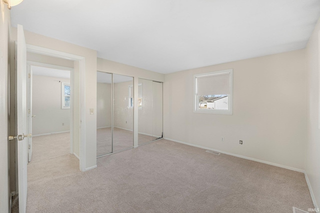 unfurnished bedroom with visible vents, multiple closets, carpet, and baseboards