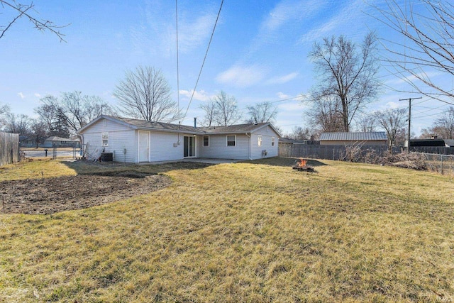 back of property featuring a fenced backyard, a lawn, and a fire pit