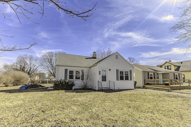 exterior space with a front yard, a chimney, roof with shingles, and a wooden deck