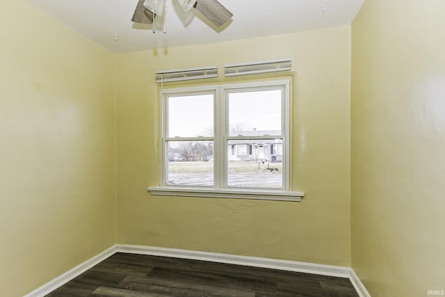 spare room featuring dark wood-style floors, a ceiling fan, and baseboards